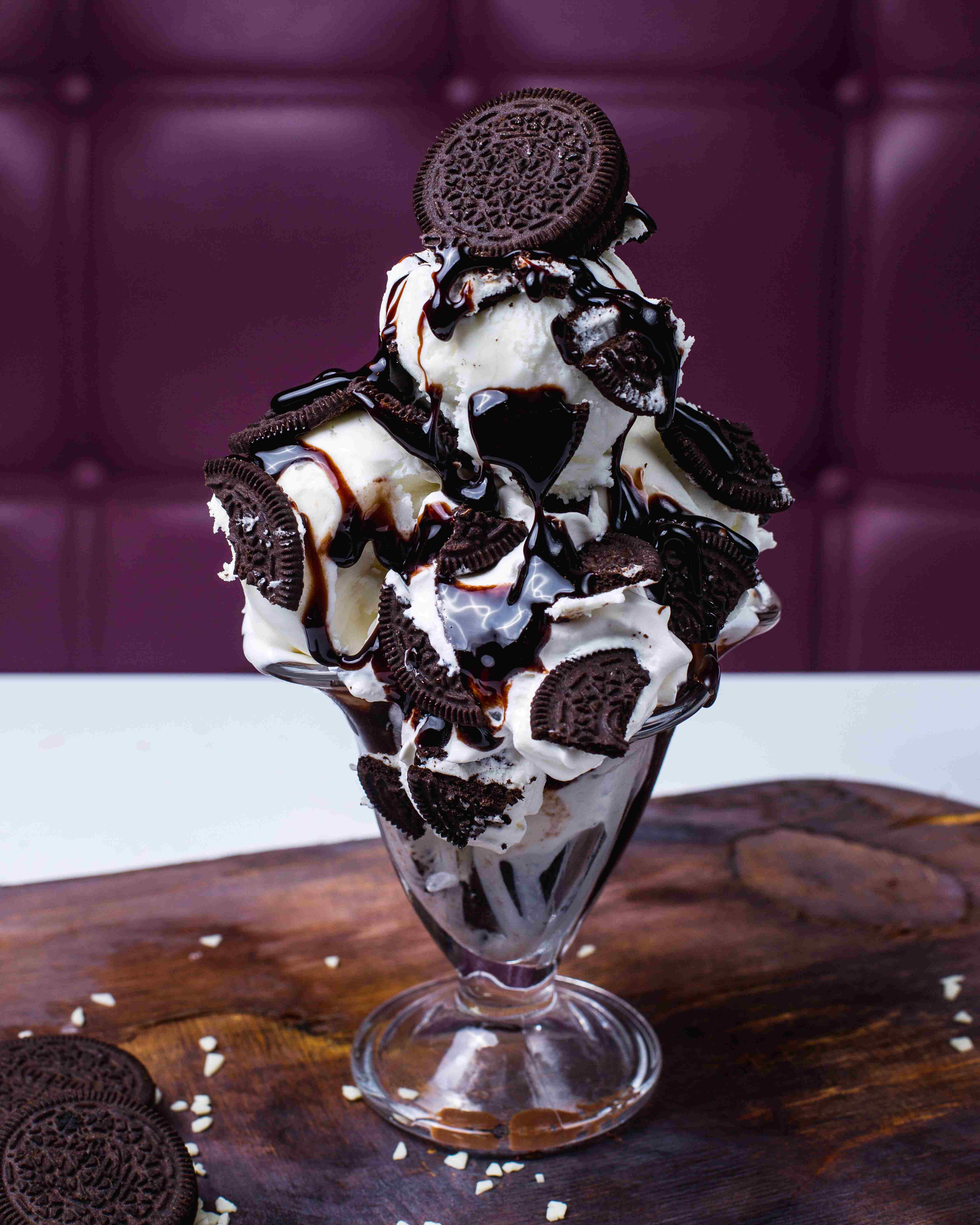 side-view-white-ice-cream-scoops-decorated-with-chocolate-cookies-syrup-vase-wooden-table.jpg