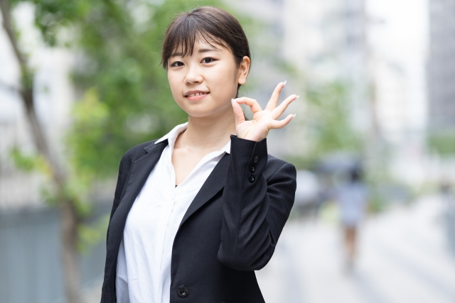 応援のポーズをするスーツ姿の女性.jpg