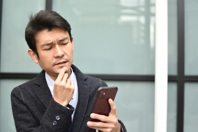 スマホ見て悩む男性.jpg