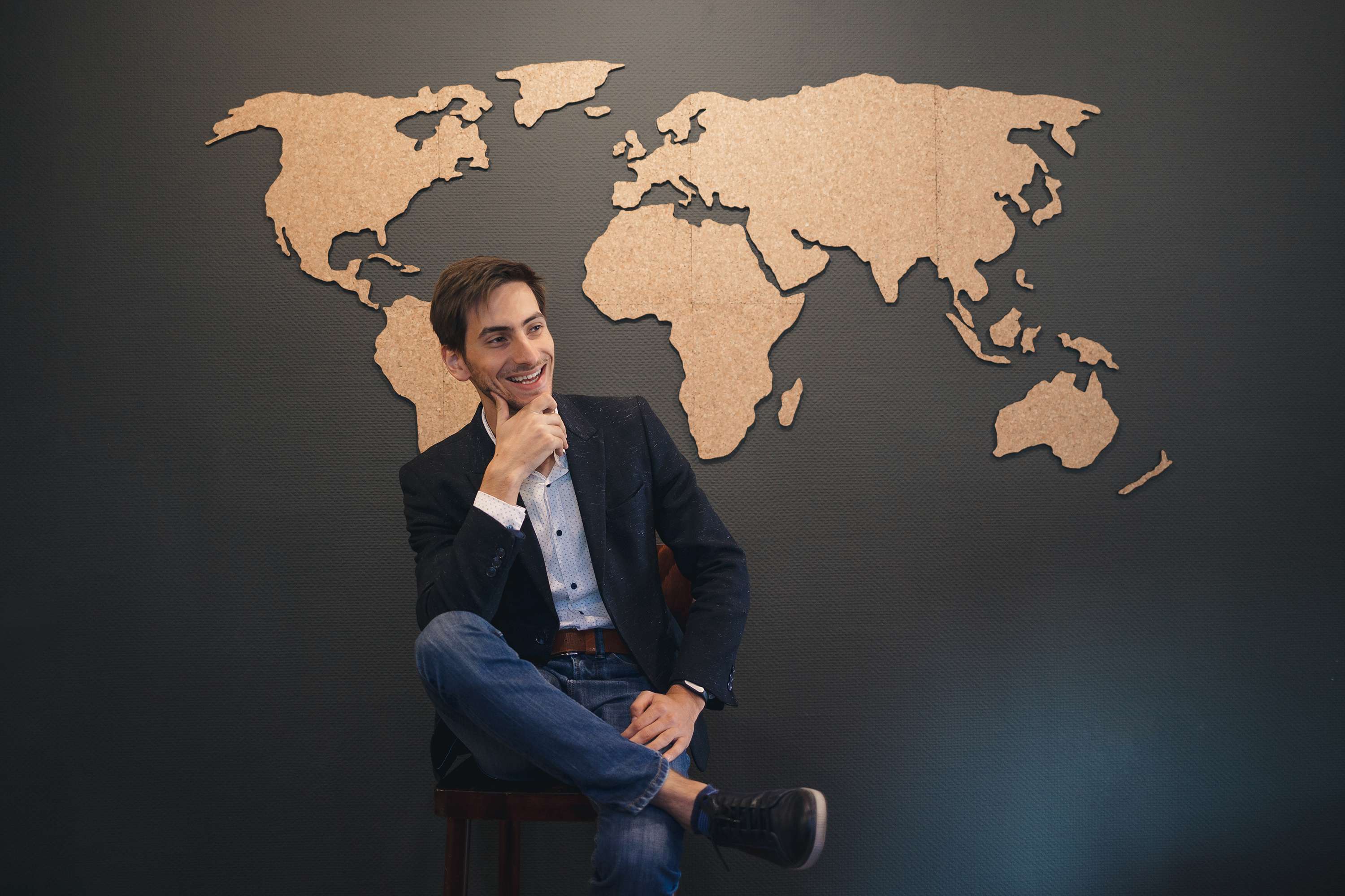 young-man-looking-to-world-map-with-crossed-hands-AYPLBL3.jpg