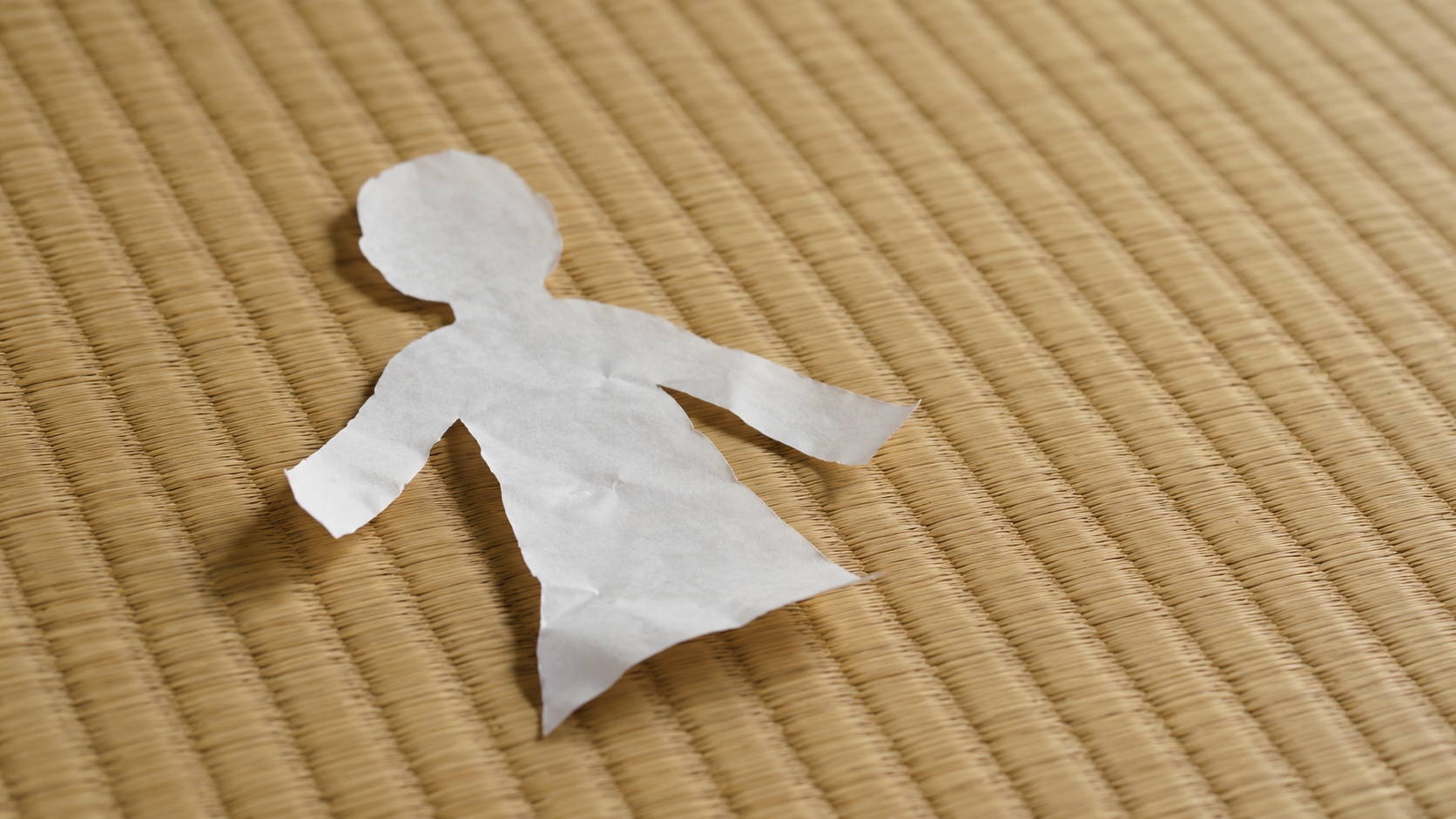畳に横たわる白い紙人形.png