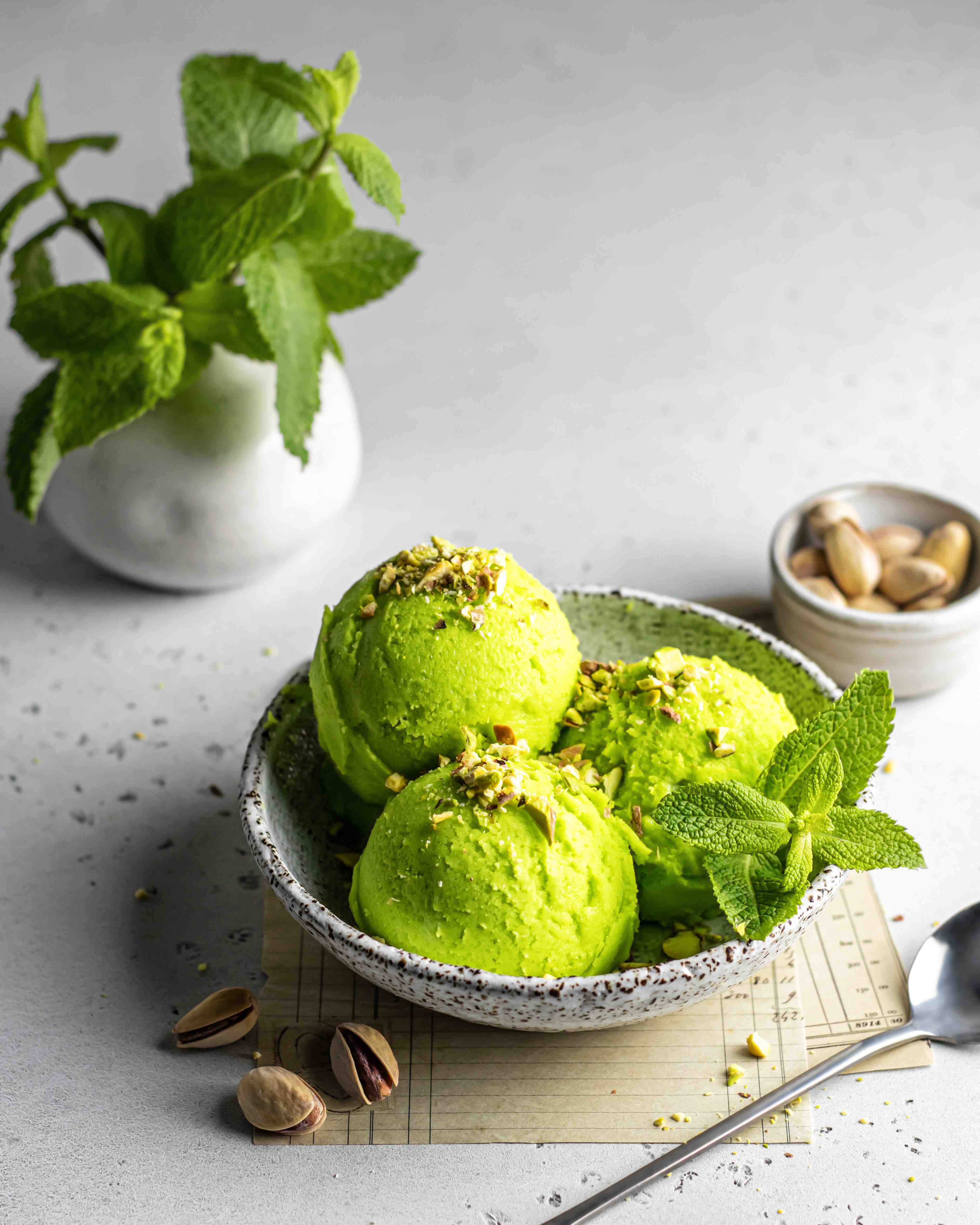 tasty-pistachio-ice-cream-with-mint-garnished-with-crushed-pistachios-textured-background.jpg